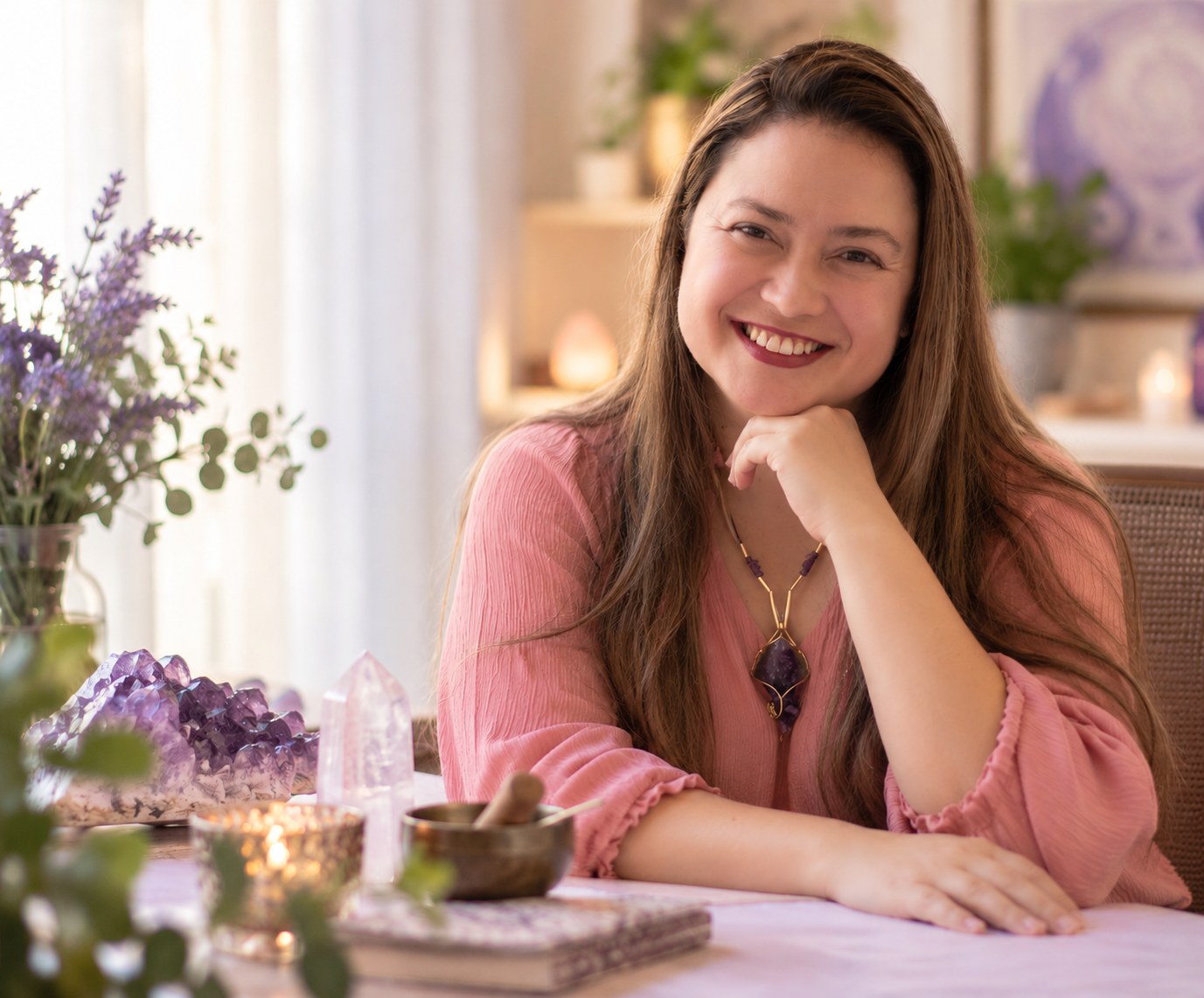 Francine Hoki sorrindo à mesa com ametista, quartzo, vela acesa e lavanda